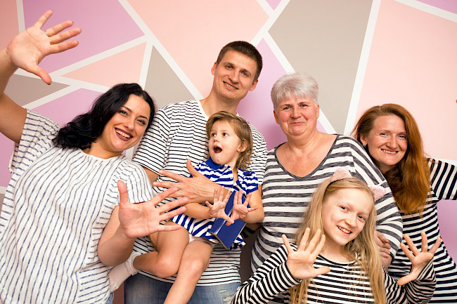 Familie mit Kindern und Großeltern winkt fröhlich in die Kamera