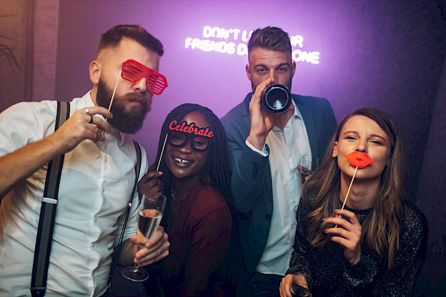 Gruppe mit Brillen-, Lippen- und Kamera-Requisiten feiert auf einer Party