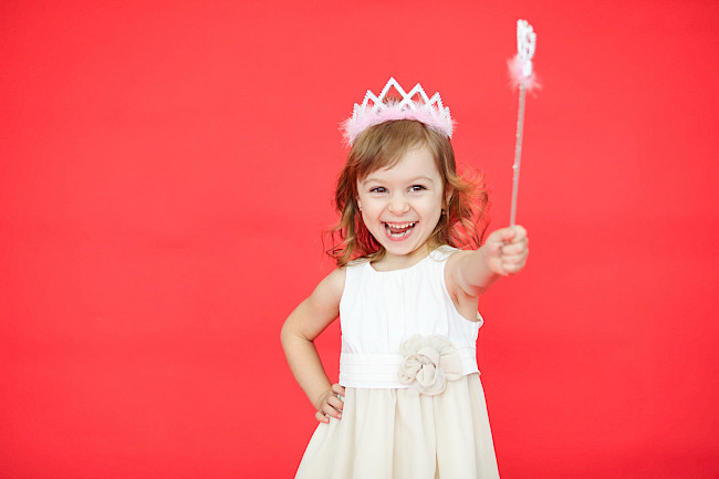 Mädchen mit Krone und Zauberstab strahlt beim Kindergeburtstag