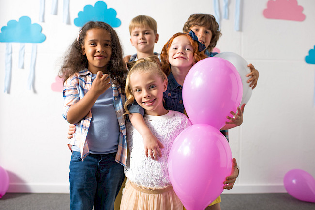 Kinder mit rosa Luftballons feiern einen Kindergeburtstag