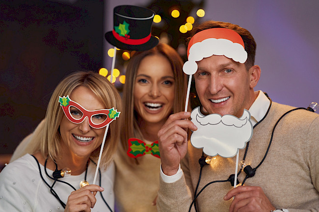 Freunde mit Weihnachtsmann-Bart, Zylinder und Brillen-Requisiten feiern Weihnachten